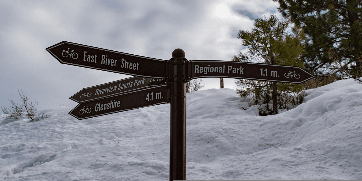 A sign at the trail junction of the Legacy Trail in Truckee. Snow in the background.