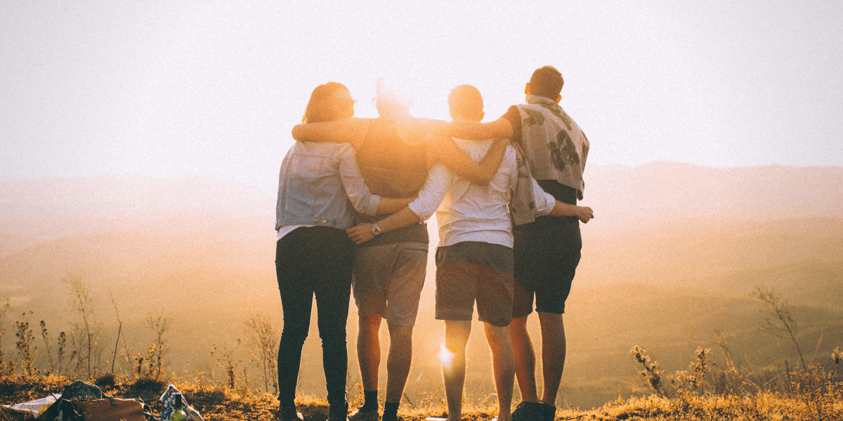 A group of friends hugging as the sun sets in the background