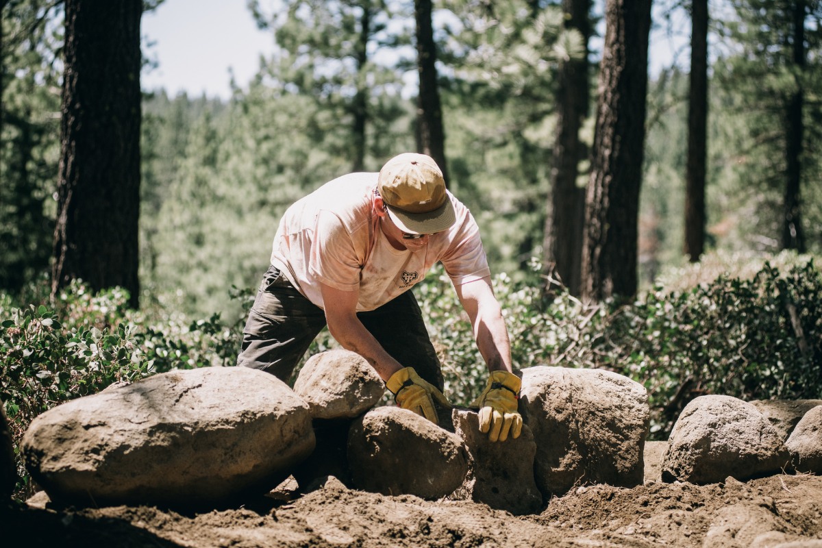 Person moving large rock along the trail at TDU's trail day.