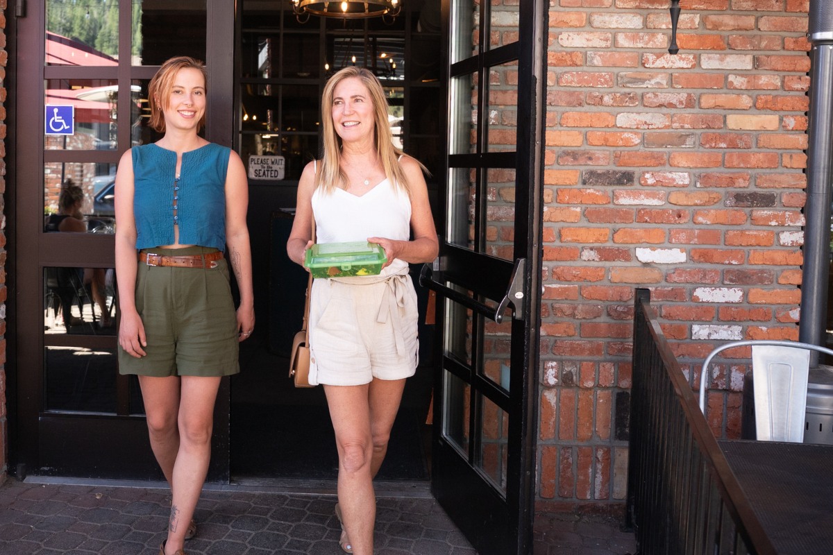 Two women using a Truckee reusable Green Box for takeout.