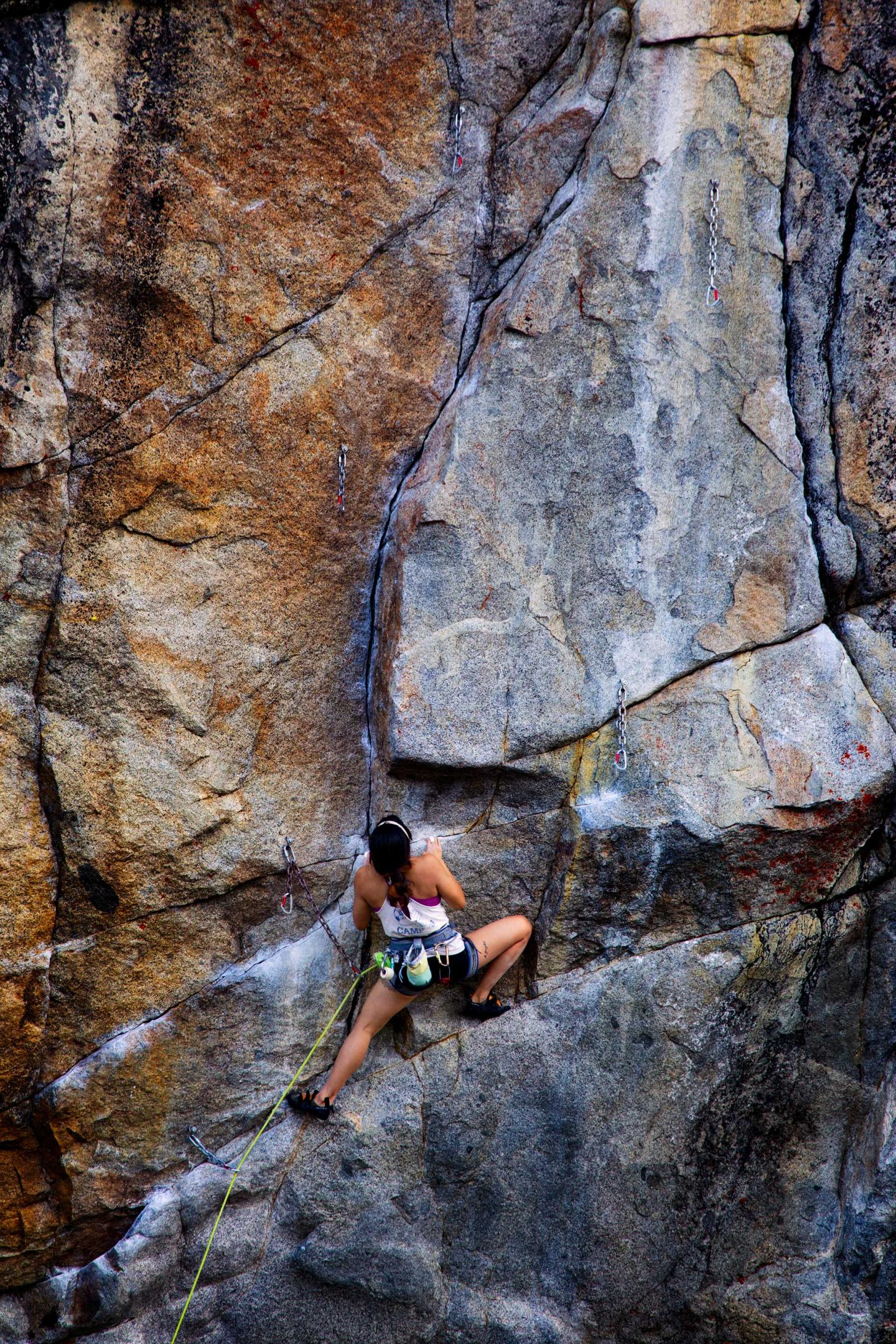 Rock climber scaling a rugged, colorful cliff face.