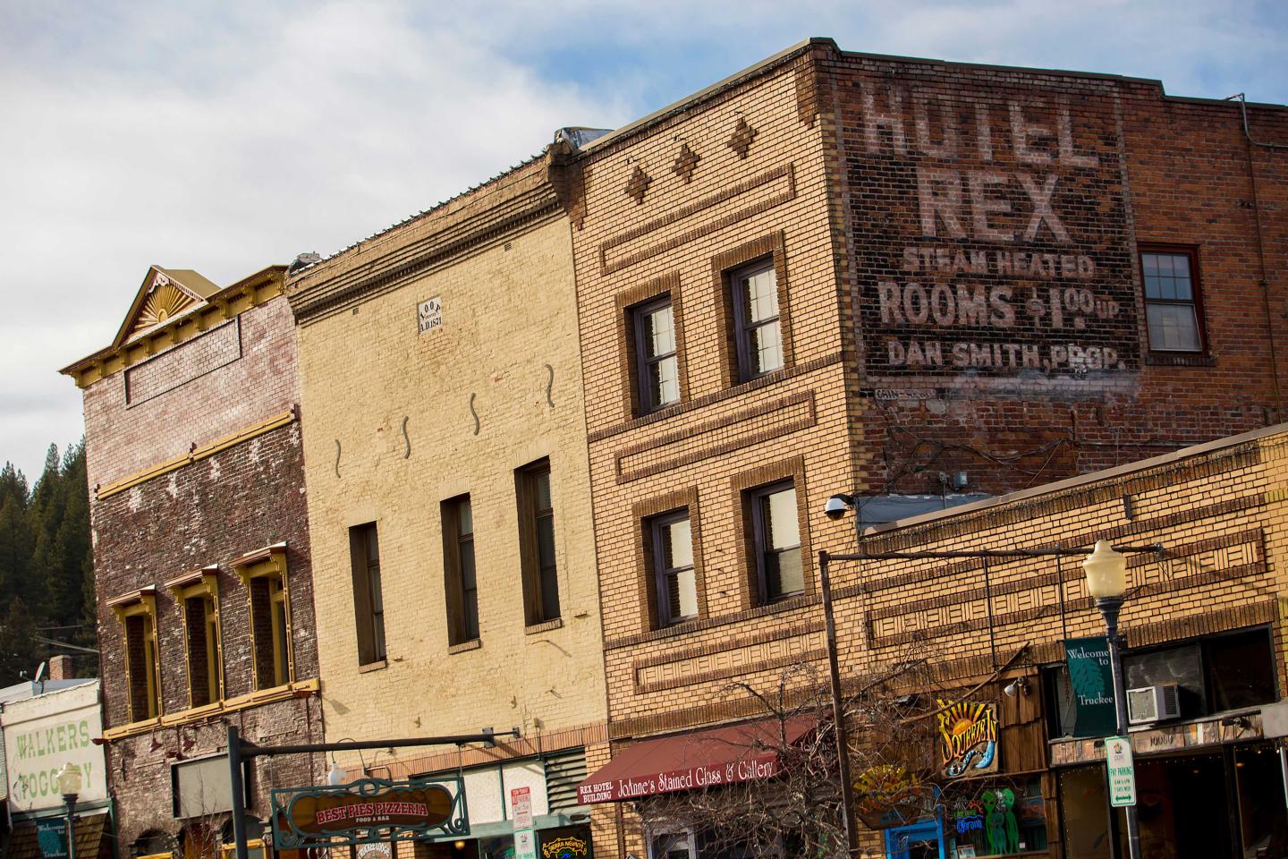 Historic brick buildings with faded signs on a sunny day.