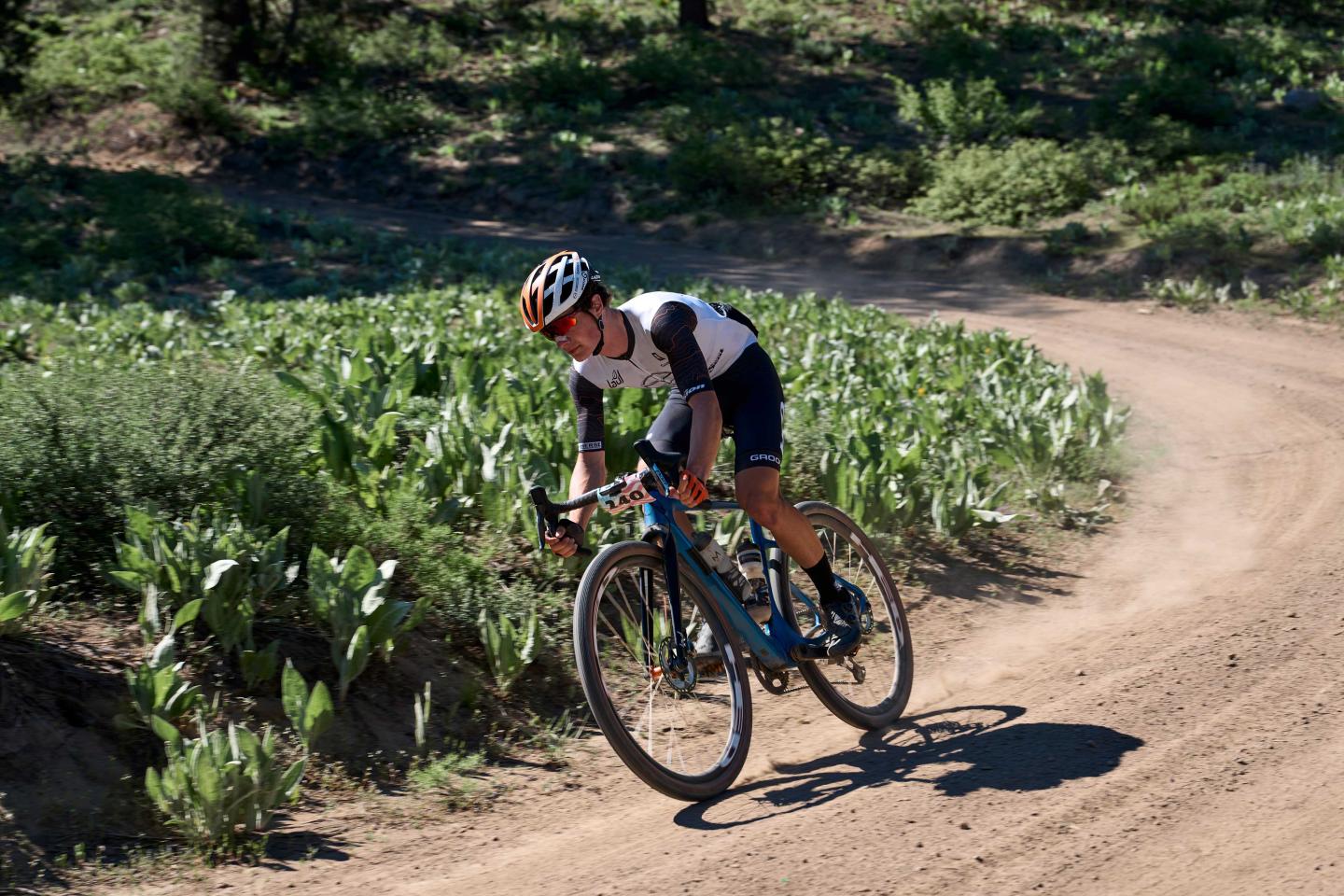 Cyclist riding on a dirt trail through green vegetation.