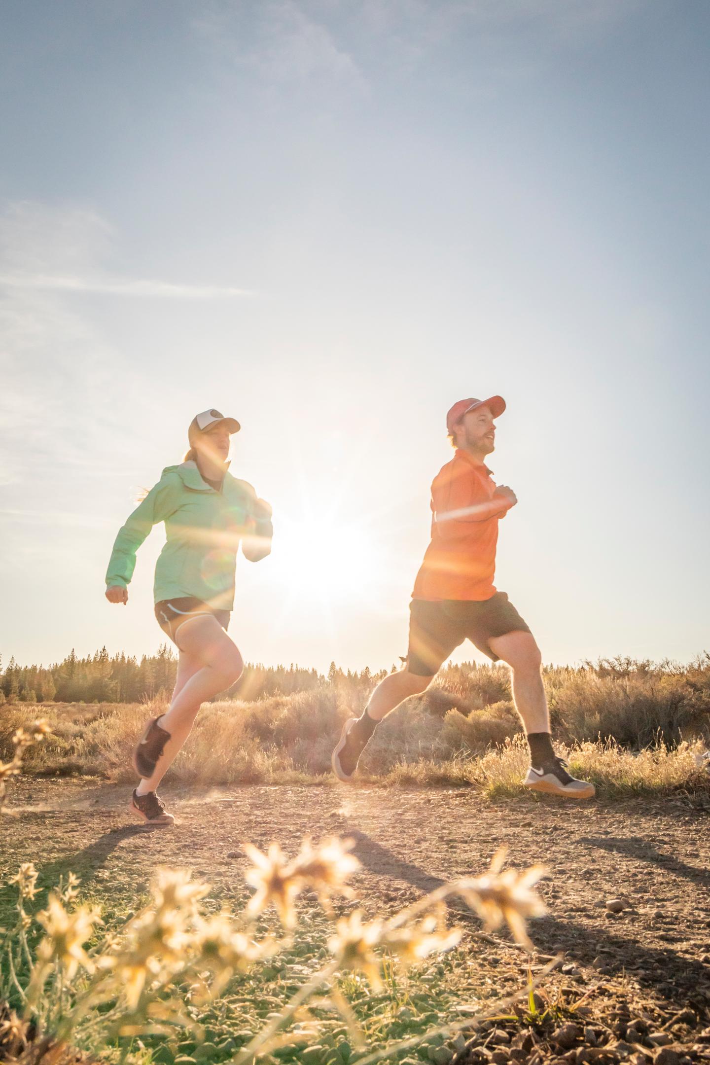Two people jogging on a sunny trail.