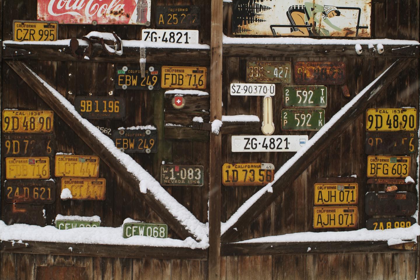 Snowy barn wall covered with vintage license plates.