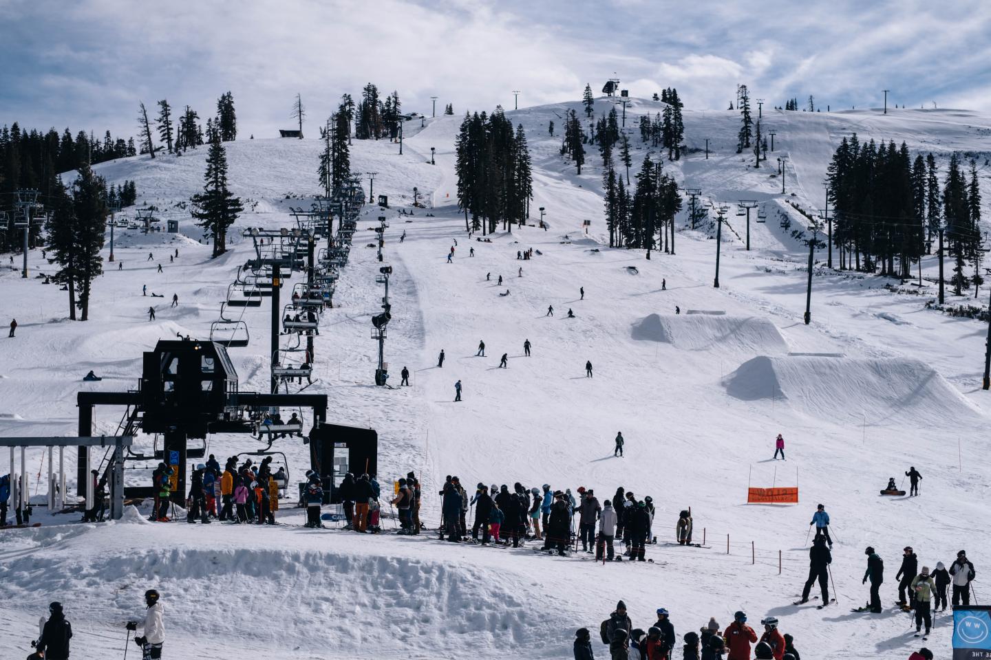 Skiers lined up at ski lift on snowy mountain.