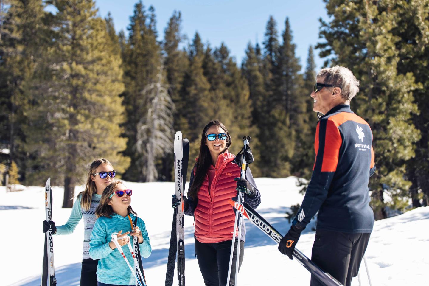 Group skiing lesson in snowy forest, sunny day.