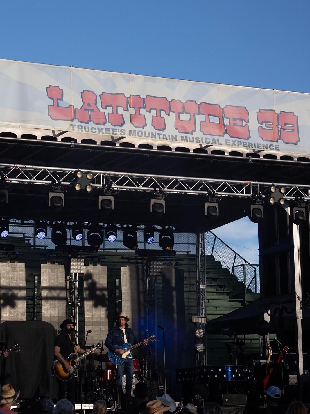 A band performing on an outdoor stage under a blue sky.