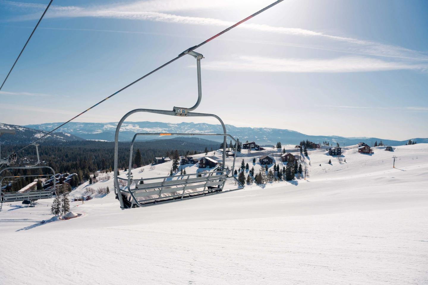 Ski lift over a snowy mountain landscape under a clear blue sky.