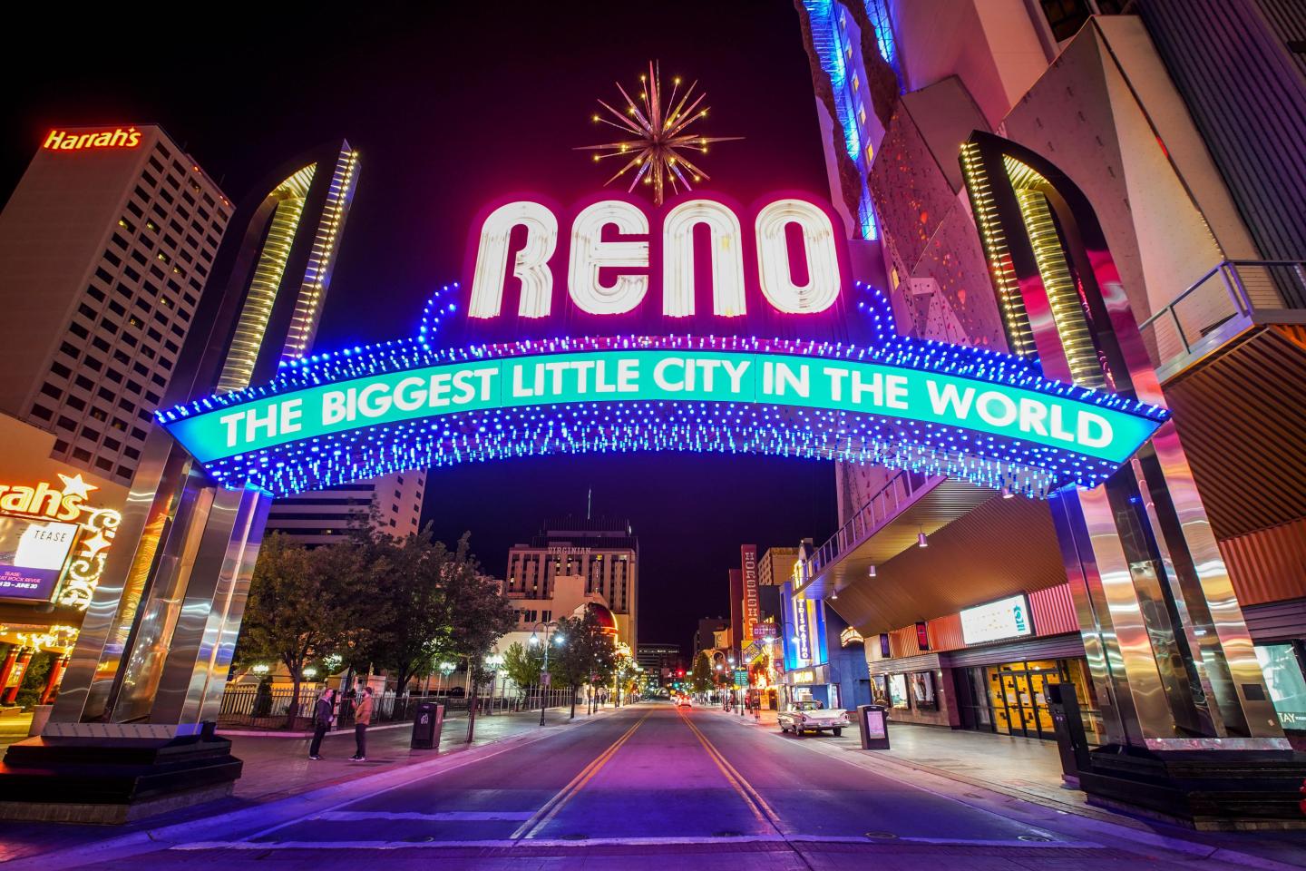 Reno city sign glowing at night on an empty street.