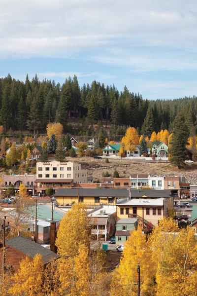 Small town with colorful autumn trees and forested hills in the background.