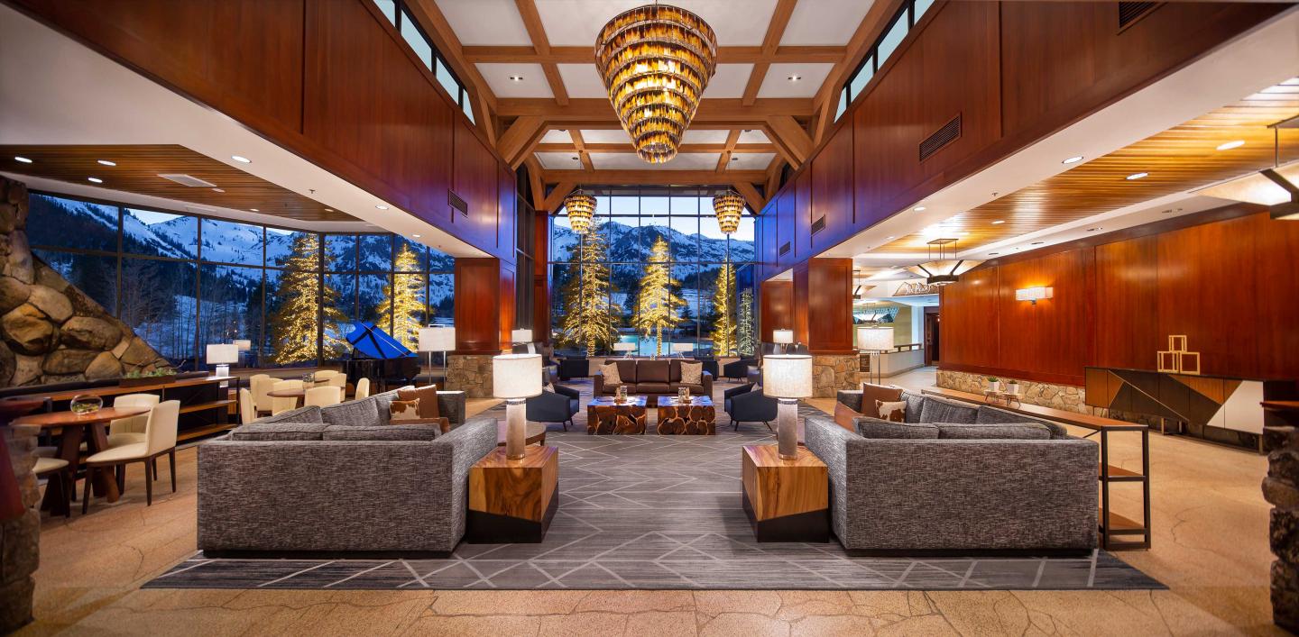 Luxurious hotel lobby with sofas, warm lighting, and large windows.