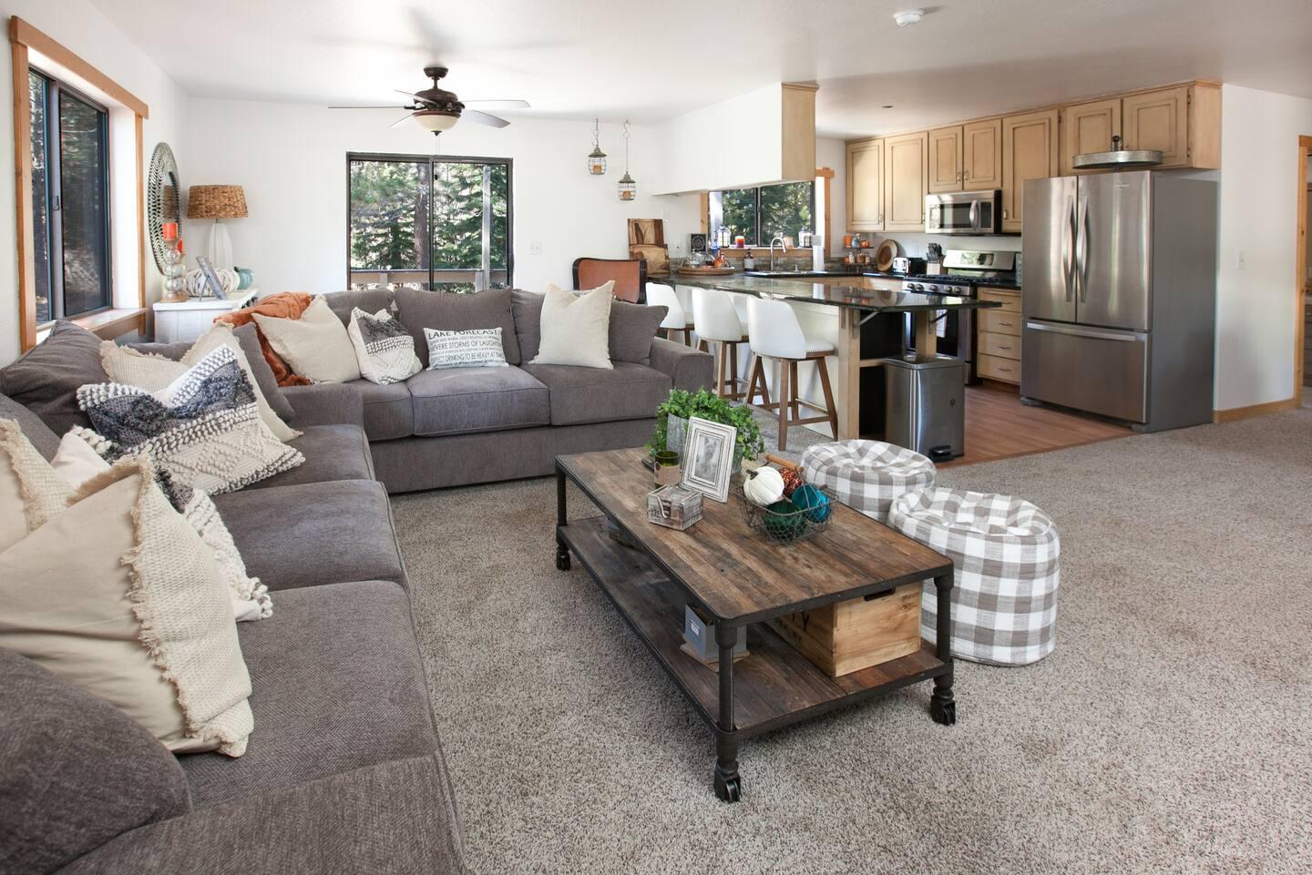 Spacious living room with gray sofas, a wooden coffee table, and an open kitchen.