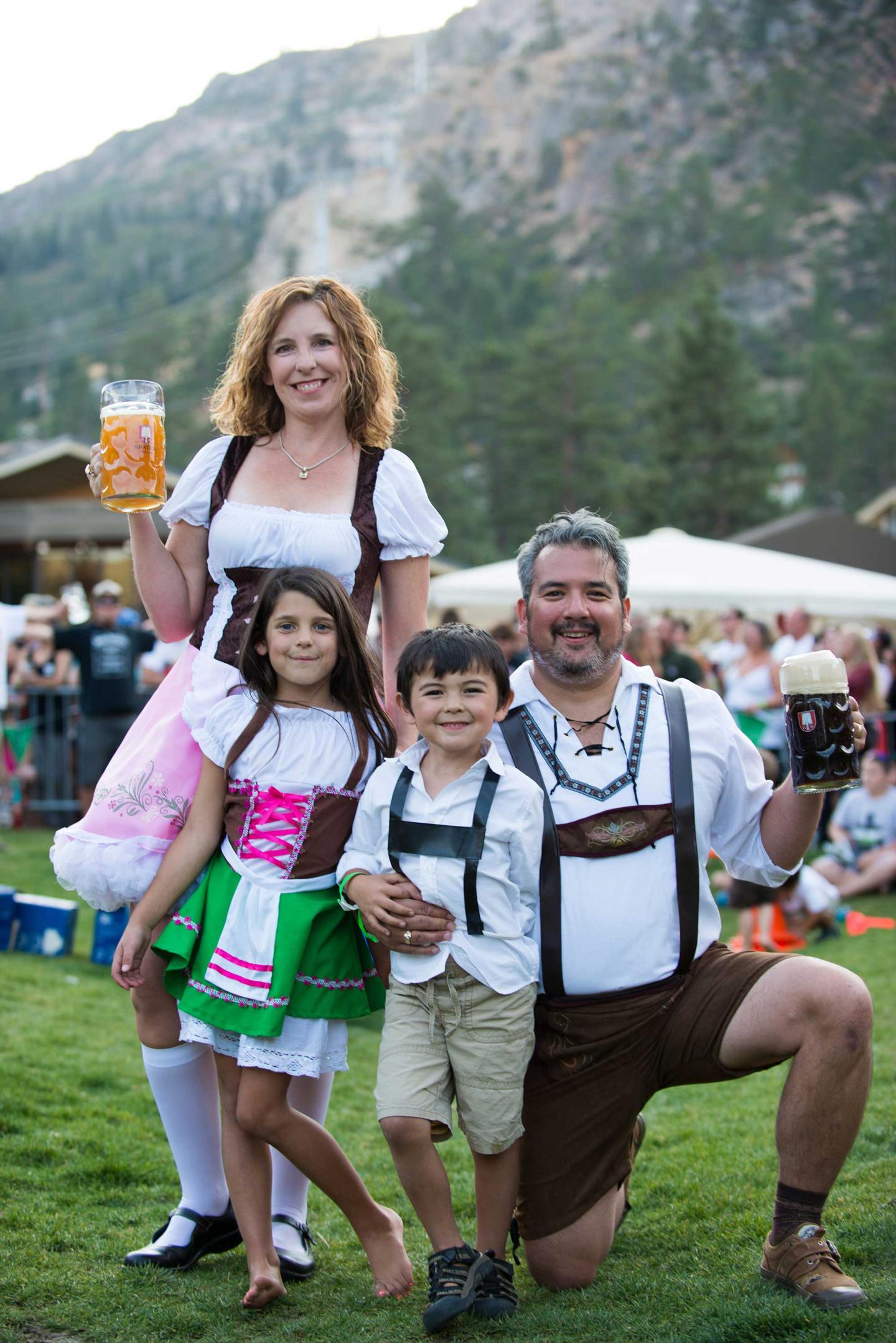 Family in traditional attire at outdoor festival with mountains in background.