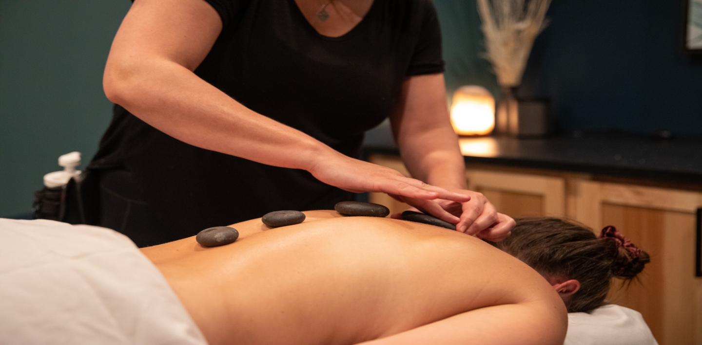 Martis Valley Massage // Therapist gives a hot stone massage in a dimly lit spa.