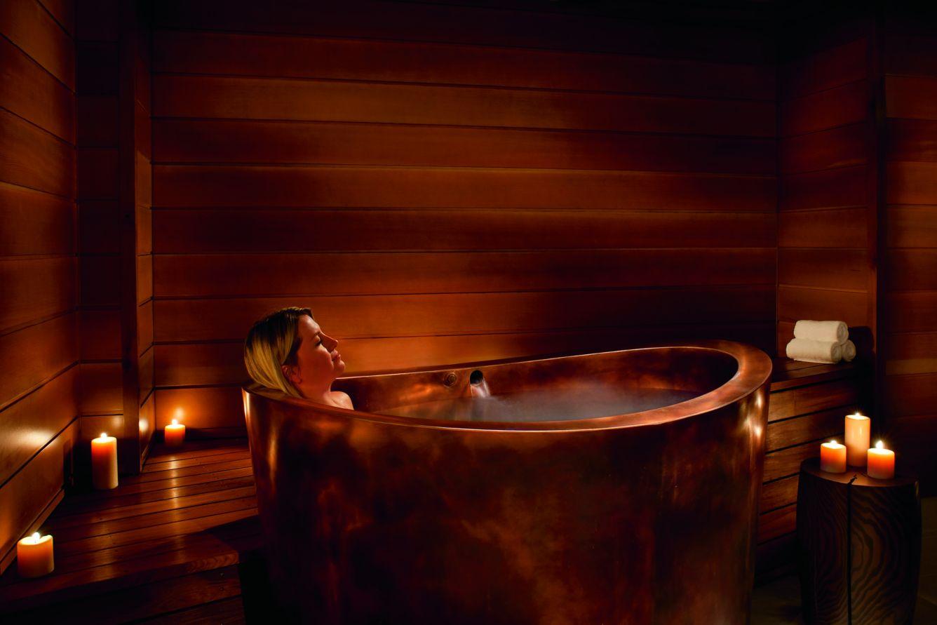 Ritz Carlton Lake Tahoe Spa // Woman relaxing in wooden bathtub surrounded by candles.