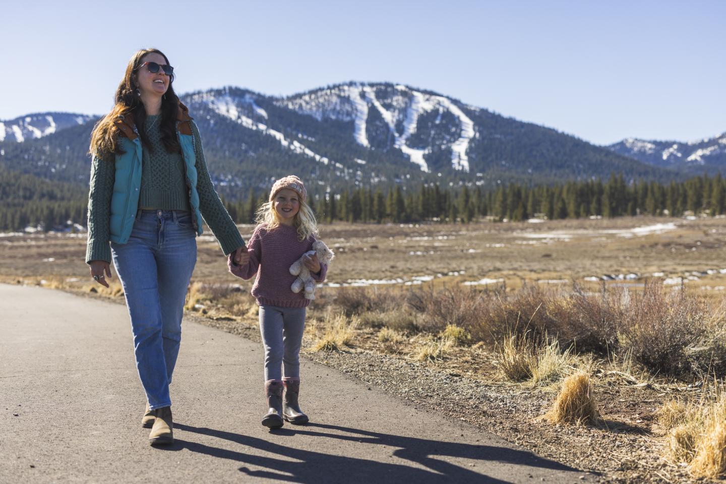 Martis Valley Trail Truckee California Mother and child walking on a road near snow-capped mountains.