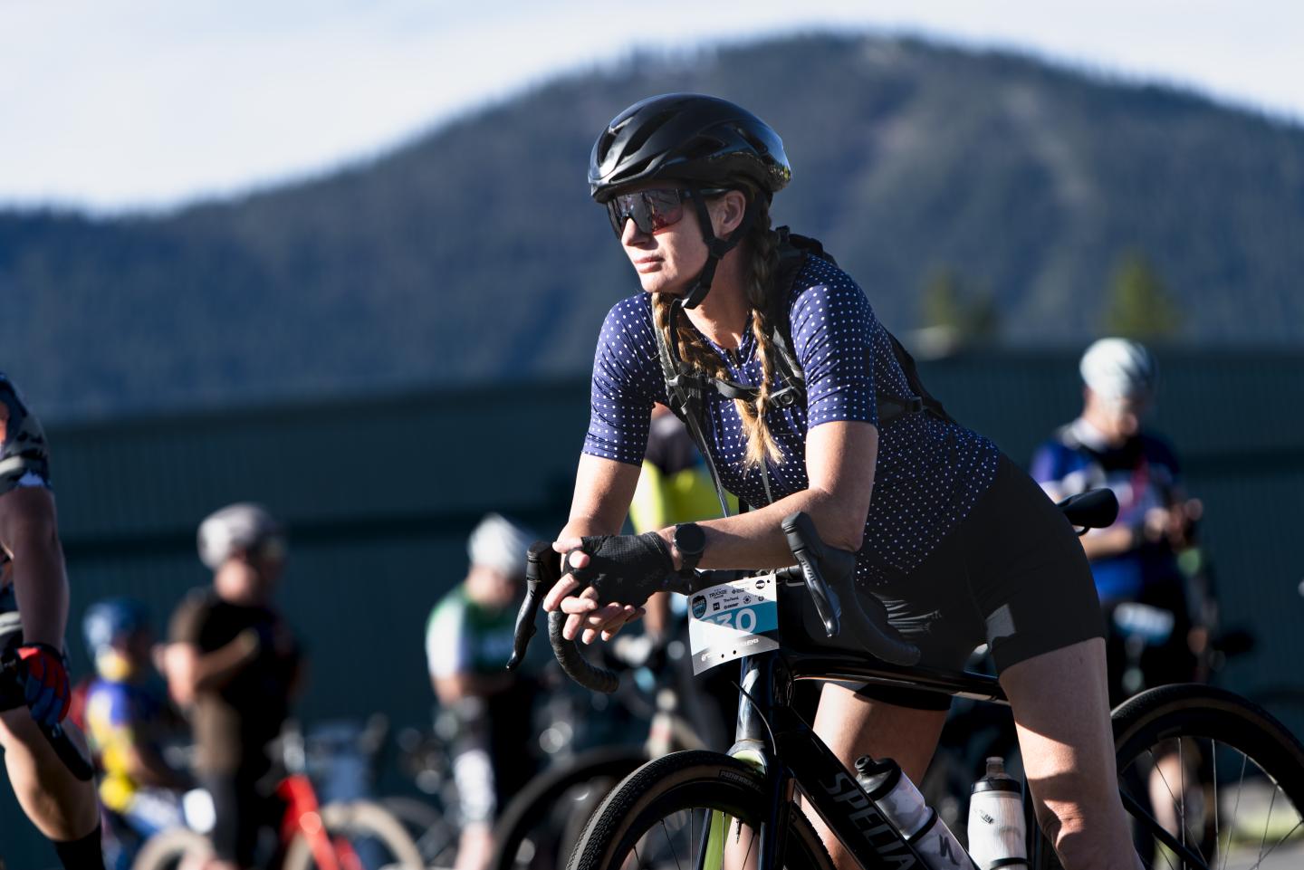 Cyclist wearing helmet and jersey, riding in mountainous area.