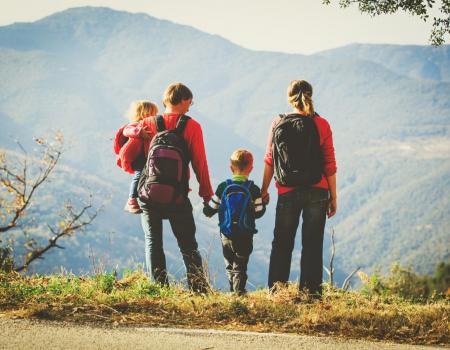 Tahoe Getaways Lodging Deal / Family hiking with mountains in the background, holding hands.