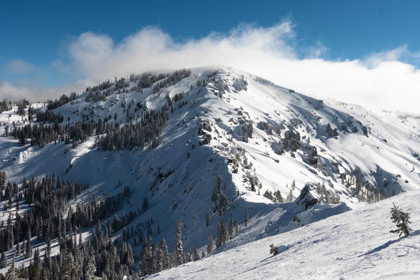 Snow-covered mountain under a clear blue sky with clouds. Sugar Bowl Ski Resort, Truckee, Tahoe