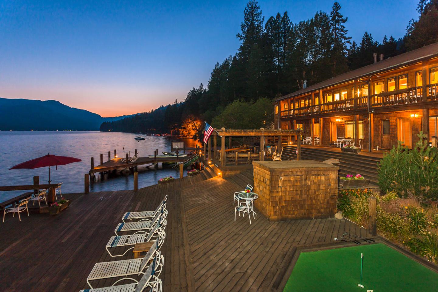 Loch Leven Lodge / Lakeside lodge at sunset with wooden decks and outdoor seating.