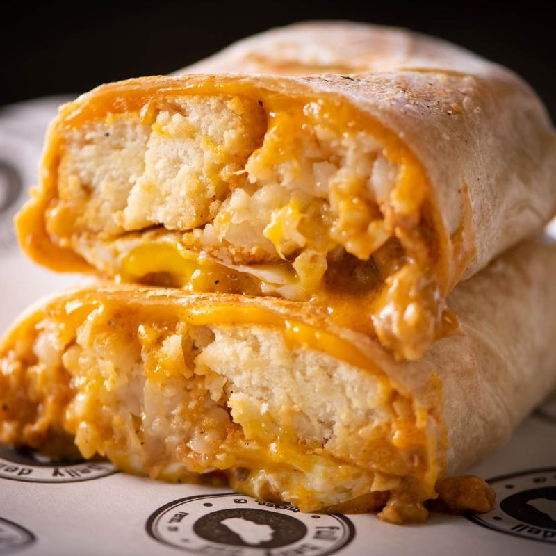 Full Belly Deli Breakfast burrito halves stacked on a paper wrapper