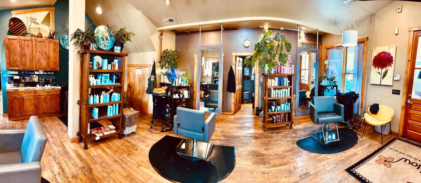 Warm, stylish salon interior with chairs, plants, and wooden flooring.