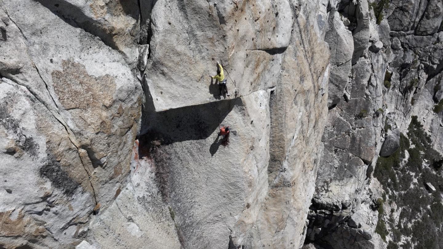 Two climbers ascending a steep rocky cliff face.