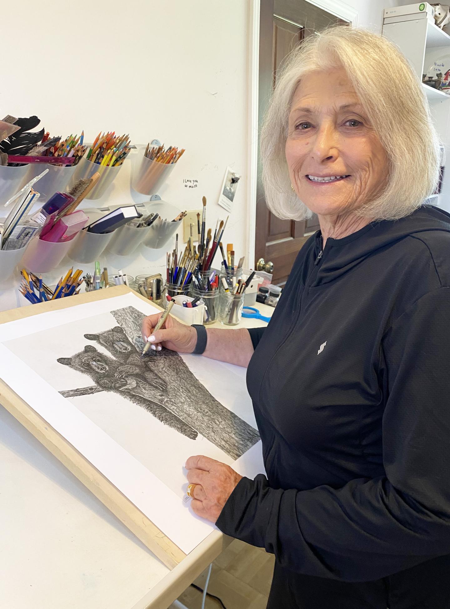 Woman smiling while drawing a dog in an art studio.