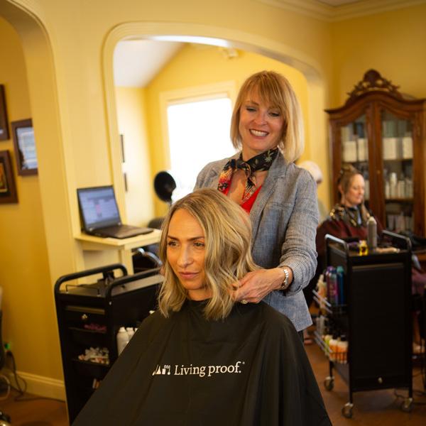 Hair stylist working on a woman's hair in a salon.