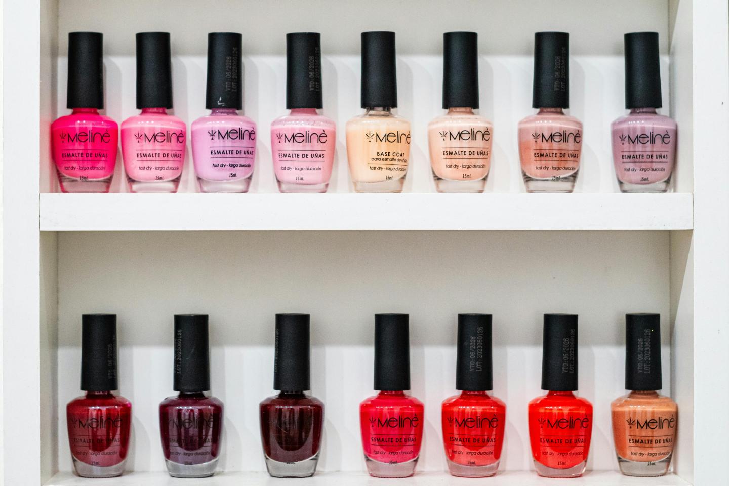 Nail polish bottles in various colors on a white shelf.
