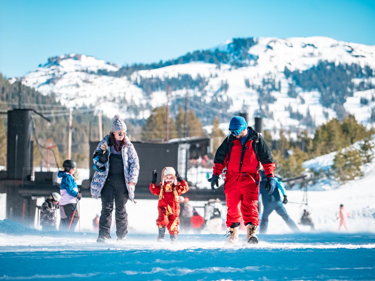 Family walking on a snowy mountain, dressed in winter gear.