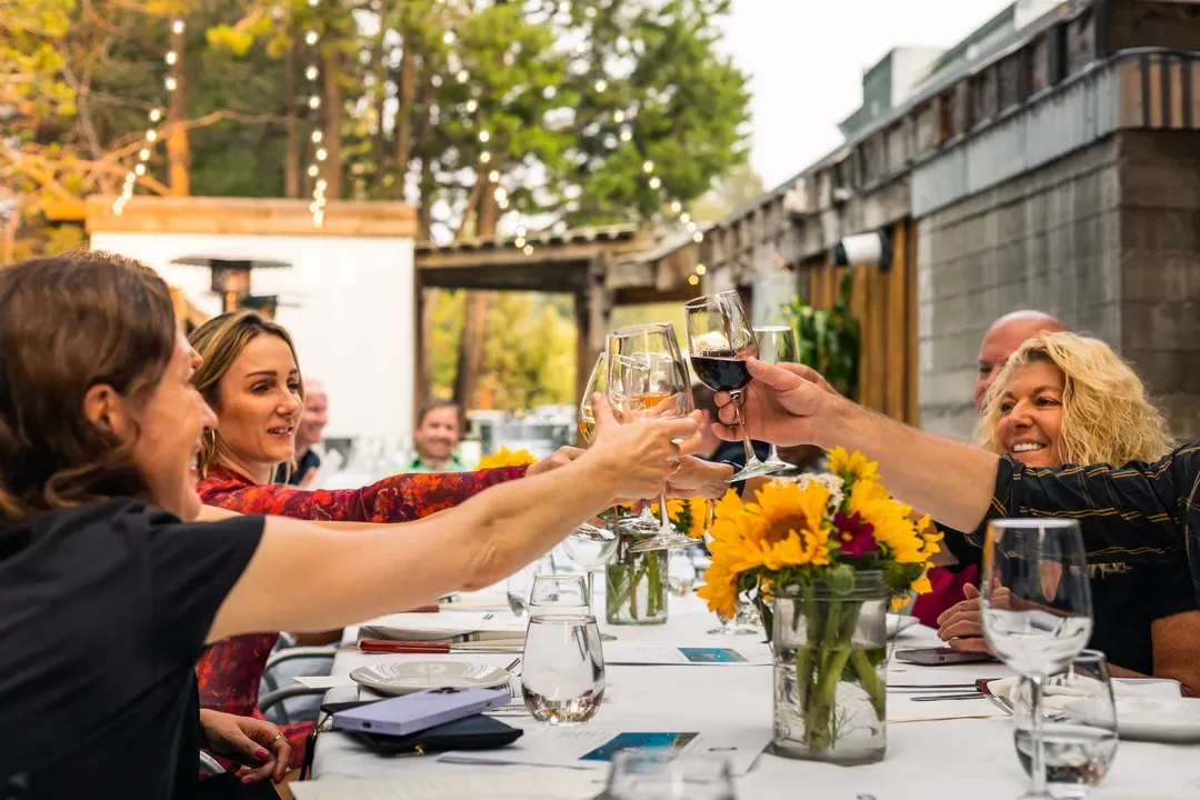 Dinner at Stella / Friends toasting with wine at an outdoor dinner table.