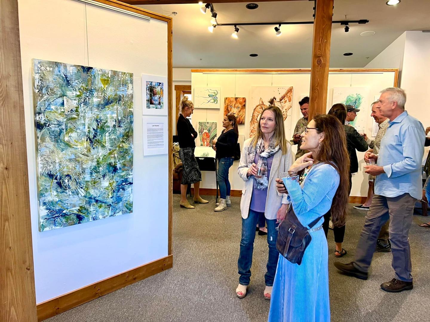 Art gallery with people viewing abstract paintings.
