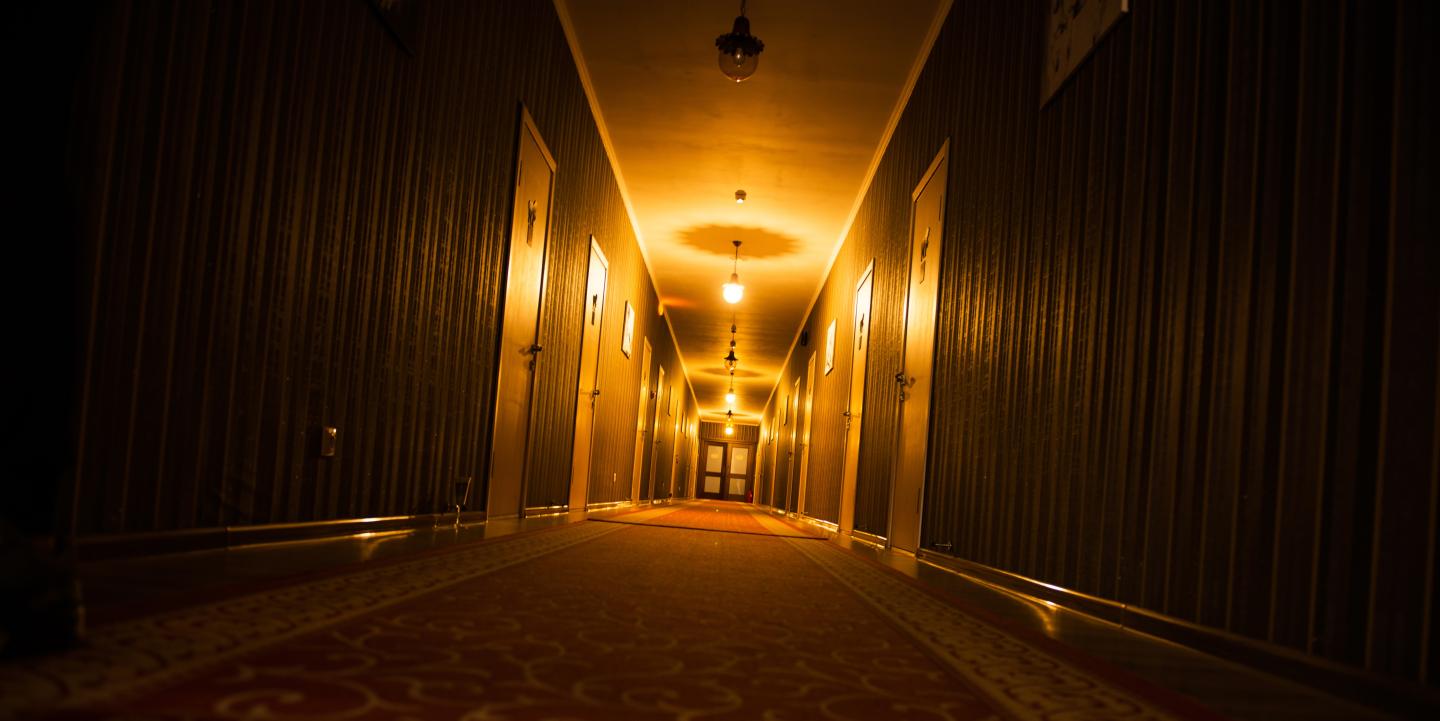 Truckee Escape Room - Dimly lit hotel corridor with warm lights and patterned carpet.