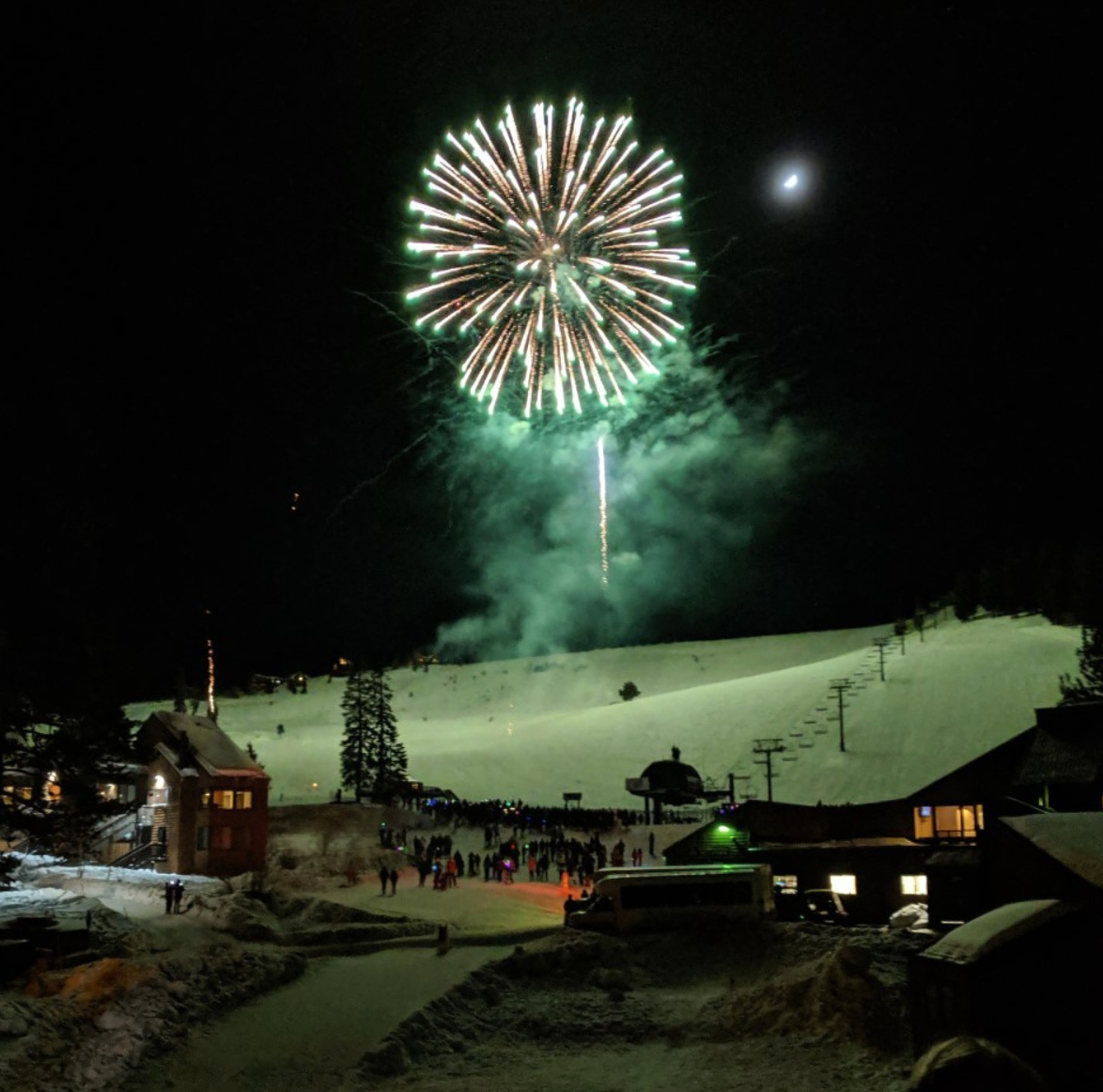 Fireworks lighting up a snowy ski resort at night.