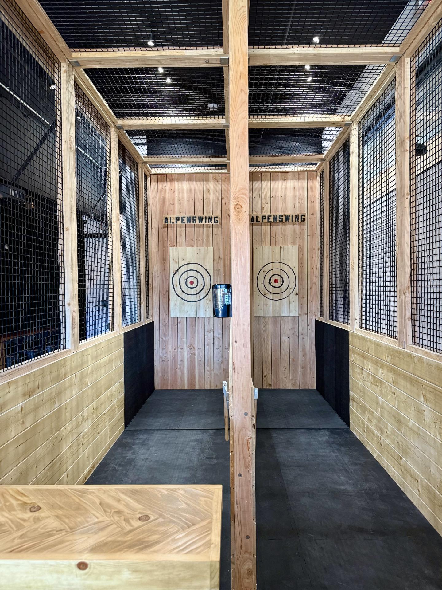 Axe throwing lanes with wooden targets in an indoor facility.