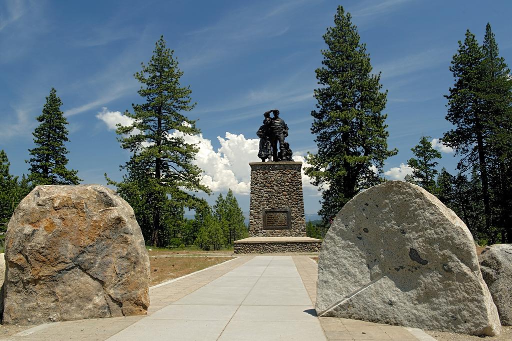 Monument with oxen and trees, flanked by large rocks under a blue sky.
