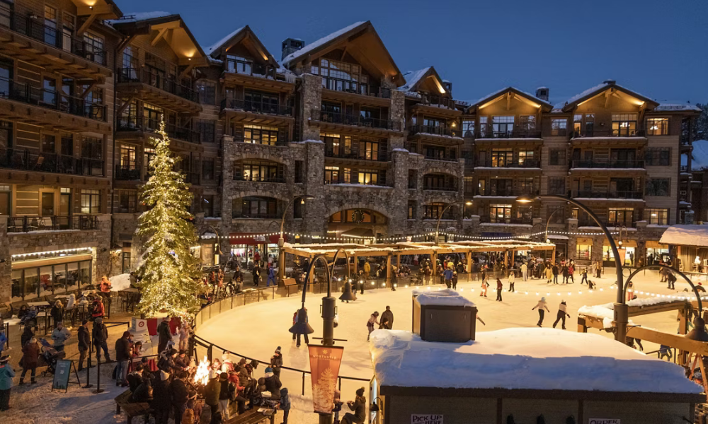Outdoor ice rink with skaters, festive lights, and a large lit-up Christmas tree.