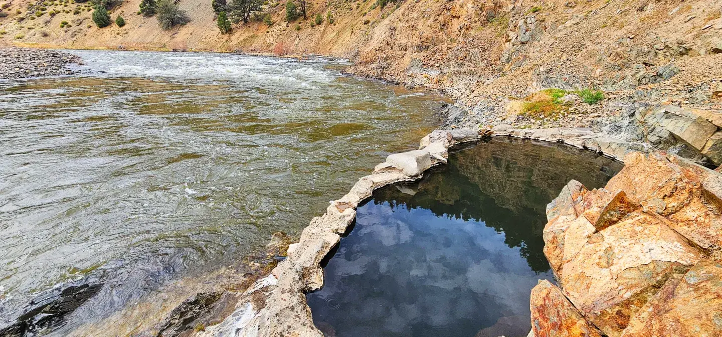 Riverside hot spring pool with rocky surroundings.