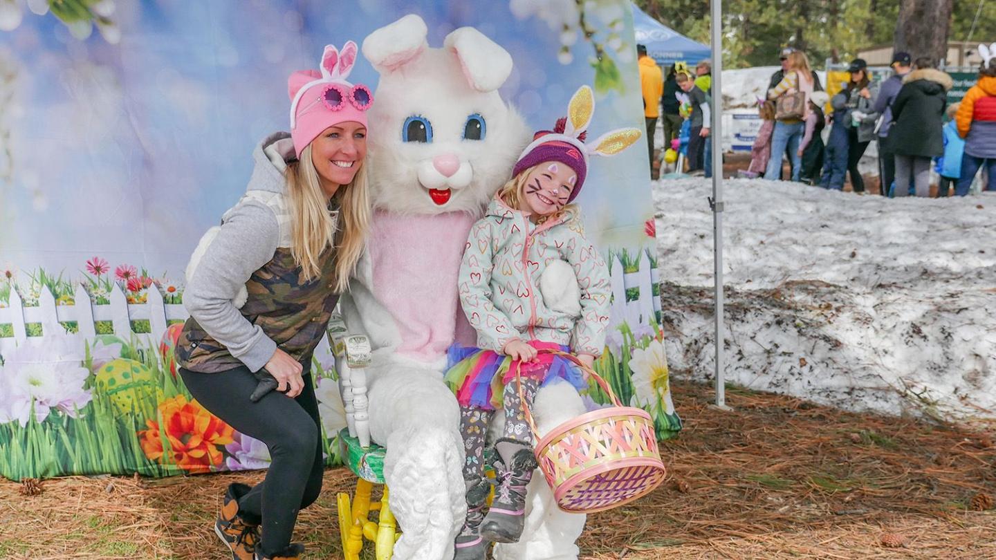 Woman and child with bunny ears posing with an Easter Bunny.