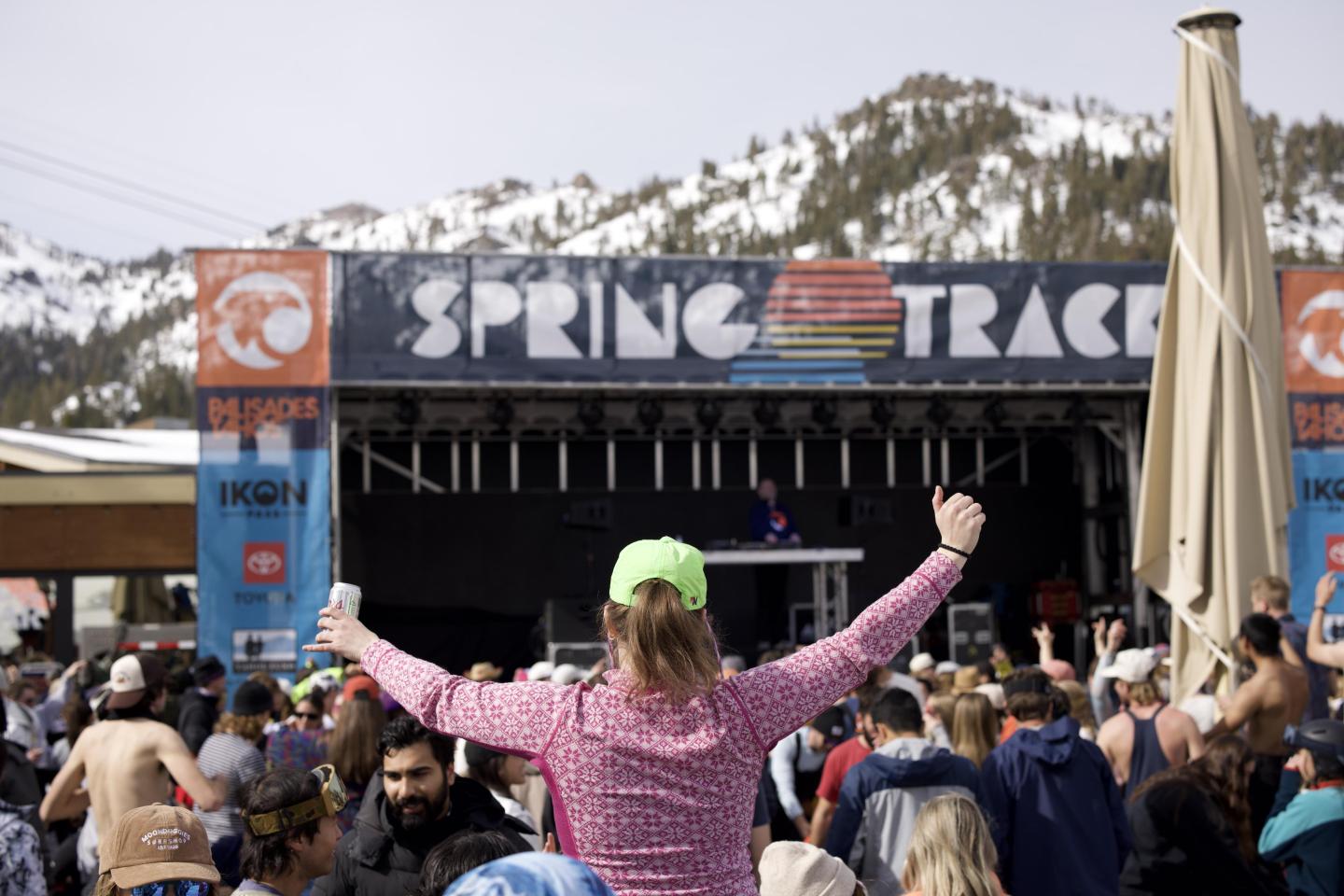 Crowd at outdoor concert with snowy mountains in the background.
