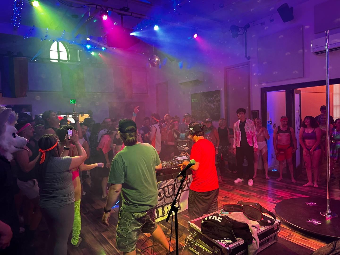 Colorful nightclub scene with people dancing under vibrant lights.