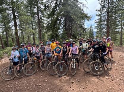Group of cyclists posing with bikes in a forest clearing.