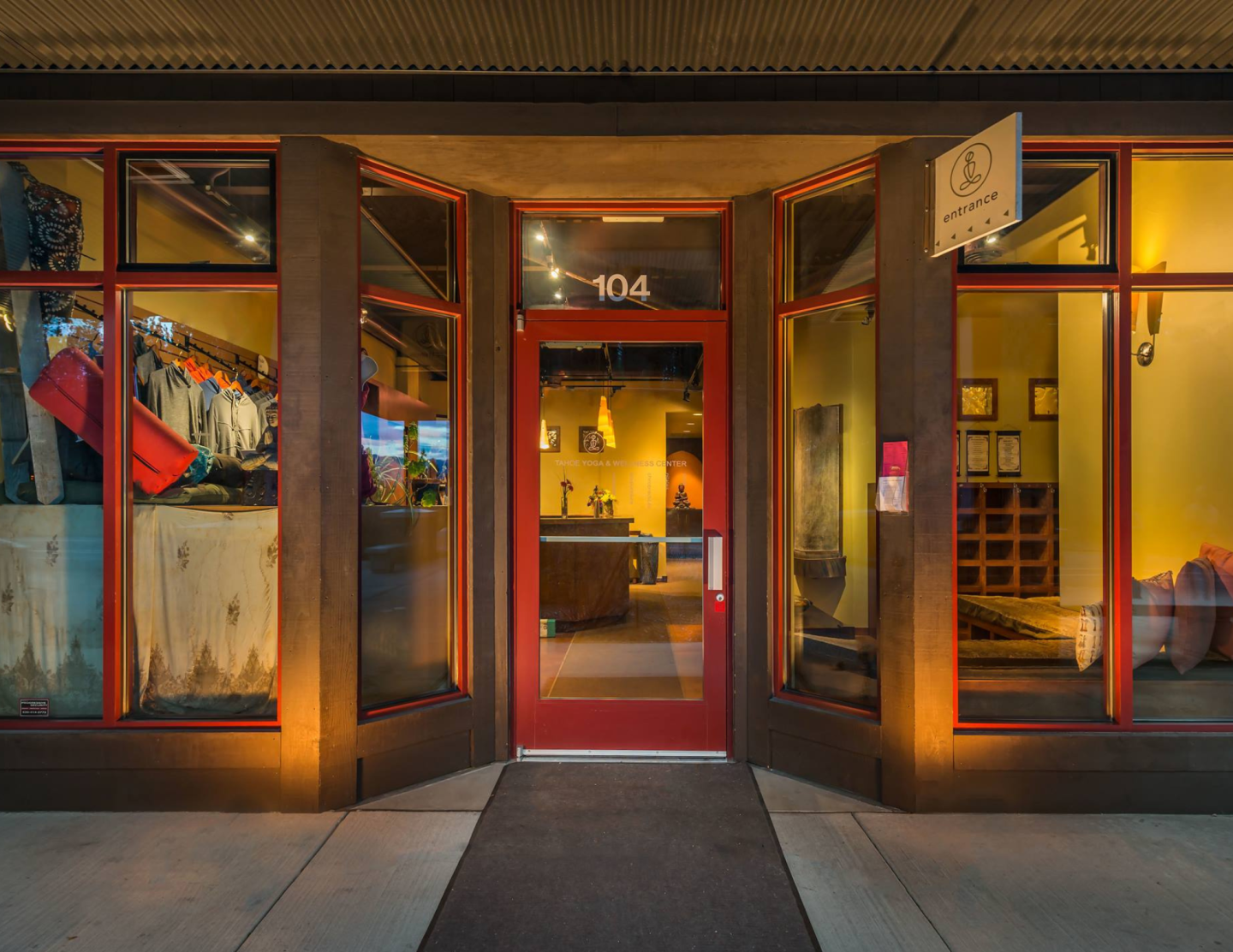 Red-framed storefront entrance illuminated at night with warm, inviting light.