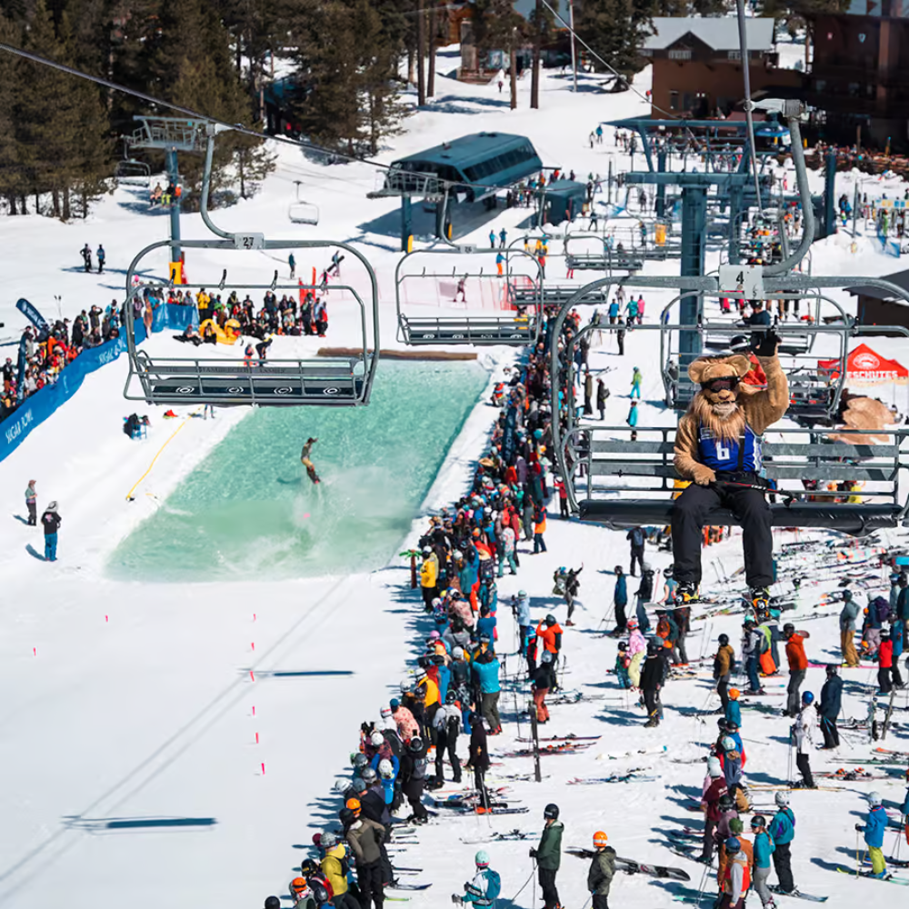 Aerial view of a ski resort with a pond skimming event and spectators.