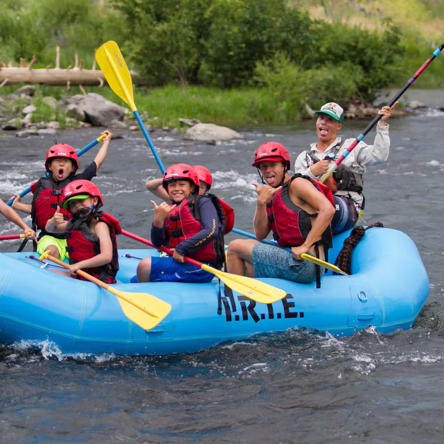 Group rafting on a river, wearing helmets and life jackets, enthusiastically paddling.