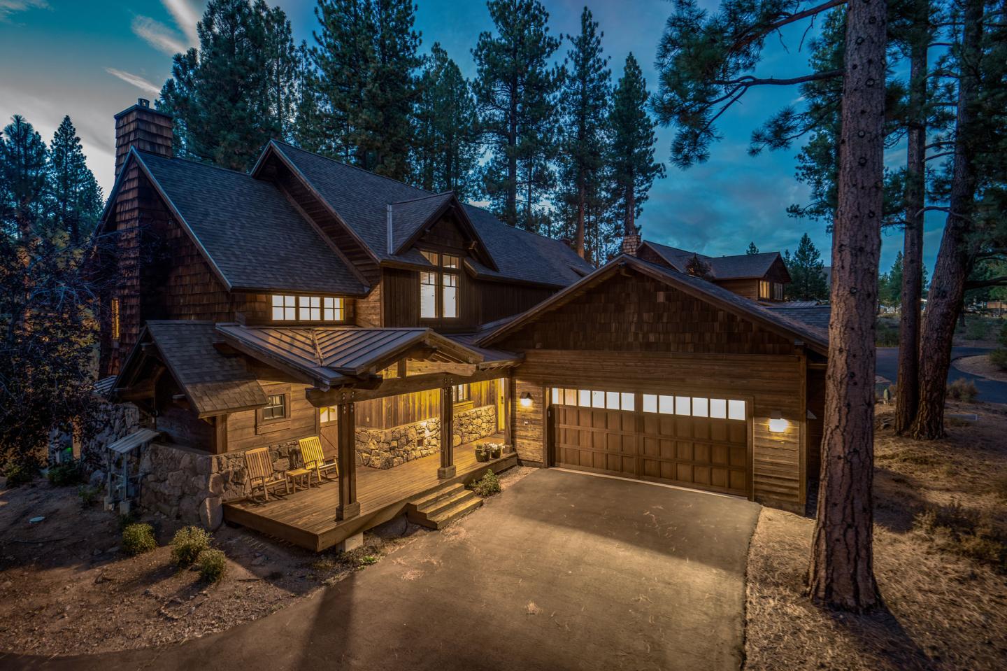 Cozy cabin with lit windows nestled among tall pine trees at dusk.