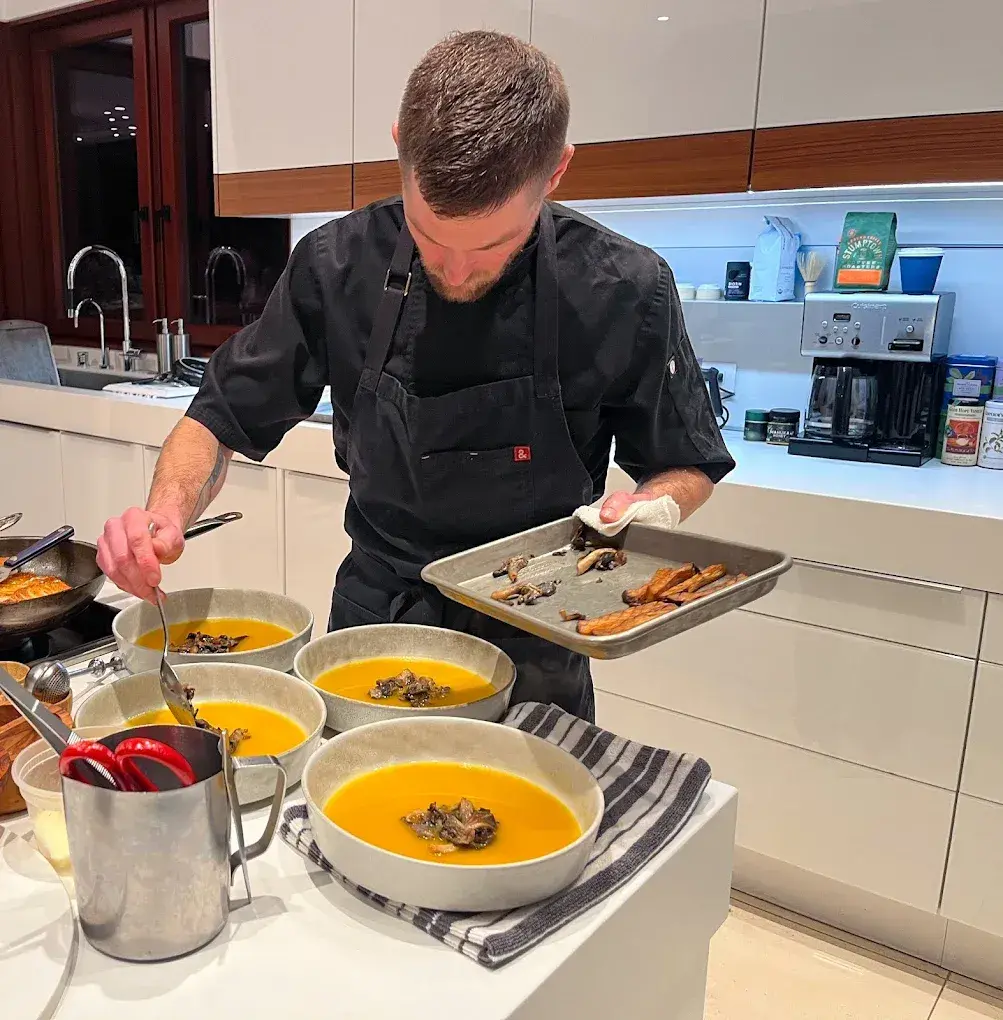 Chef plating soup in a modern kitchen.