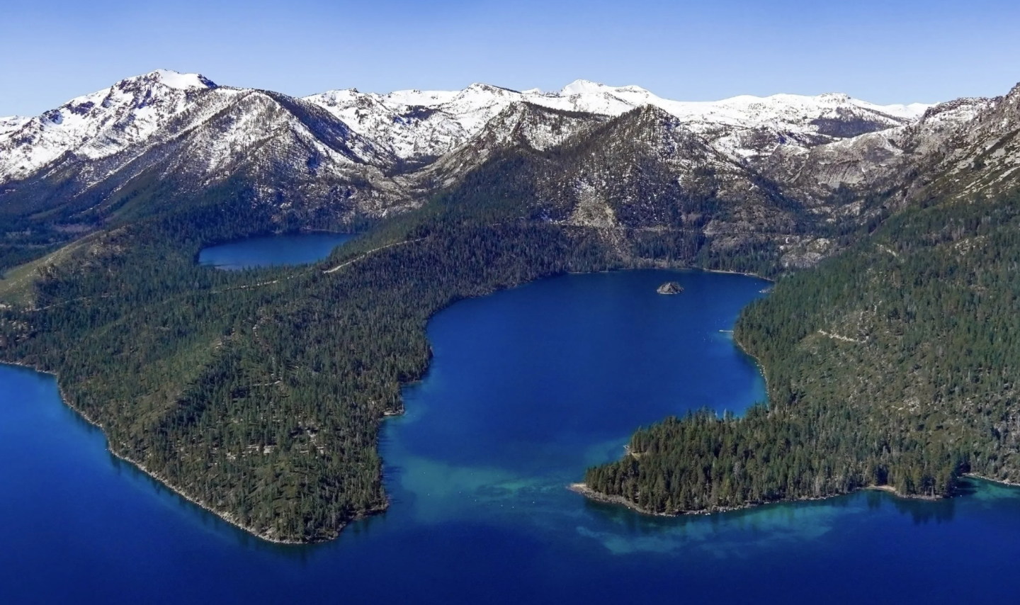 Snow-capped mountains and a blue lake with forested shores.